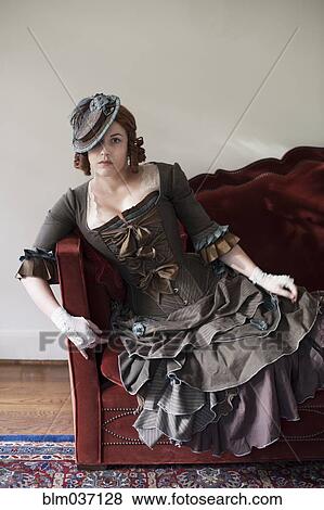 Woman wearing vintage gown and hat on sofa View Large Photo Image Stock Photo - Woman wearing vintage gown and hat on sofa. Fotosearch