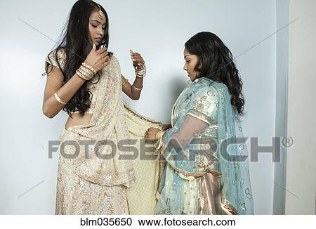 Stock Image - Woman wrapping friend in traditional dress. Fotosearch