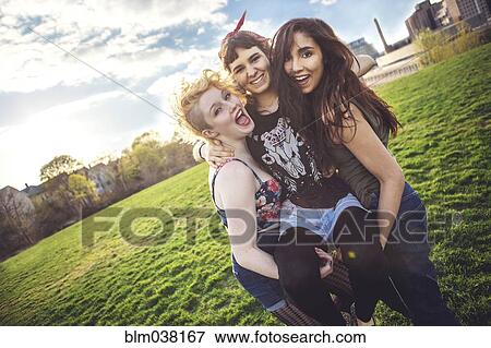 Stock Photo - Women carrying friend in urban park. Fotosearch