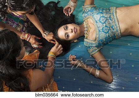 Picture - Women styling hair of woman laying on floor. Fotosearch