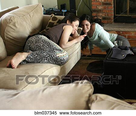 Stock Photography - Women using cell phone in living room. Fotosearch