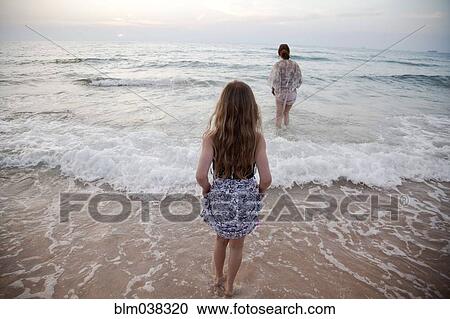 Women walking in ocean waves on beach View Large Photo Image Stock Image - Women walking in ocean waves on beach. Fotosearch