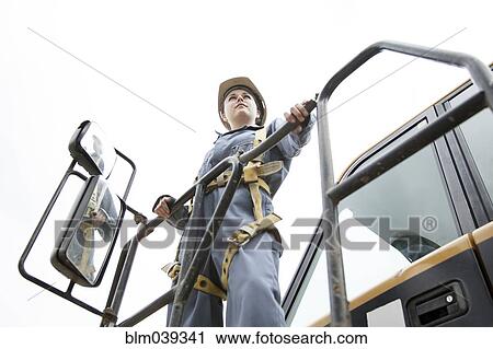 Stock Image - Worker wearing harness at construction site. Fotosearch