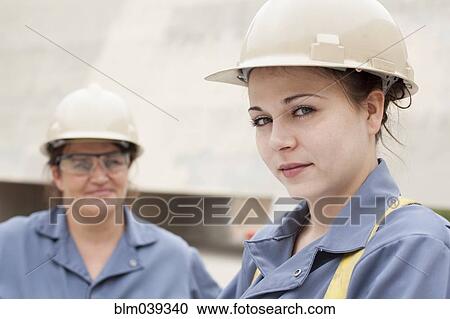 Stock Image - Workers wearing hard-hats and uniforms at work. Fotosearch
