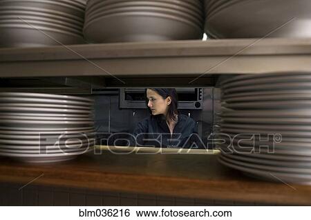 Working chef viewed through stacks of plates in restaurant kitchen View Large Photo Image Stock Photograph - Working chef viewed through stacks of plates in restaurant kitchen. Fotosearch