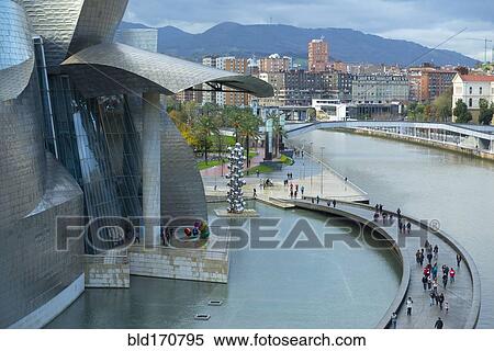 Stock Photography - Aerial view of tourists on walkway over urban canal, Bilbao, Biscay, Spain. Fotosearch