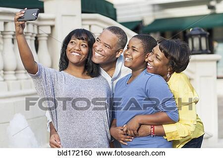 Stock Image - African American family taking selfie in city. Fotosearch