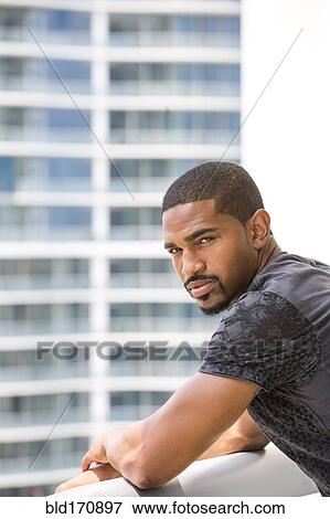 Stock Photo - African American man standing on urban balcony. Fotosearch