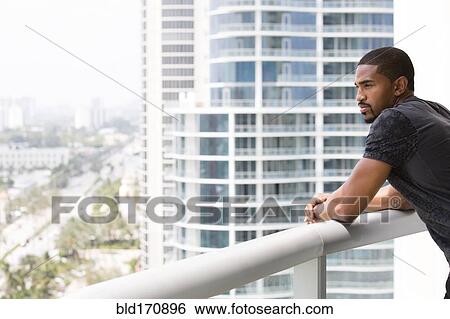 Stock Photograph - African American man standing on urban balcony. Fotosearch