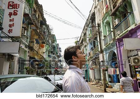 Picture - Asian businessman standing in city. Fotosearch
