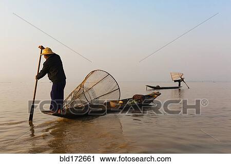 Asian fisherman rowing canoe on still lake View Large Photo Image Stock Image - Asian fisherman rowing canoe on still lake. Fotosearch