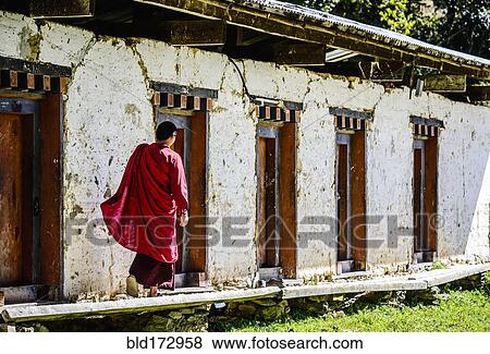 Stock Photo - Asian monk walking by monastery doors. Fotosearch