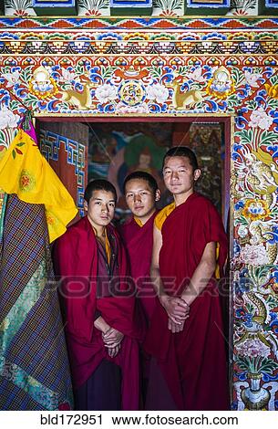 Stock Image - Asian monks standing in temple doorway. Fotosearch
