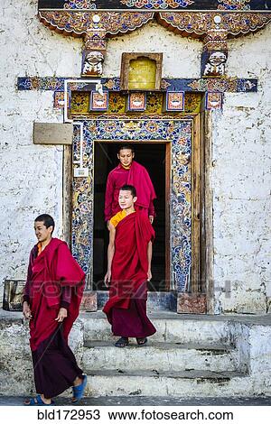 Stock Image - Asian monks walking out temple doorway. Fotosearch