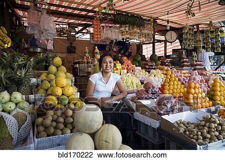 Stock Image - Asian vendor smiling at market. Fotosearch