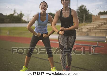 Stock Photo - Athletes flexing their muscles on sports field. Fotosearch