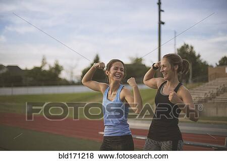 Stock Photo - Athletes flexing their muscles on sports field. Fotosearch