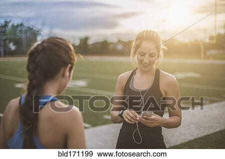 Athletes listening to mp3 players on sports field View Large Photo Image Stock Photo - Athletes listening to mp3 players on sports field. Fotosearch