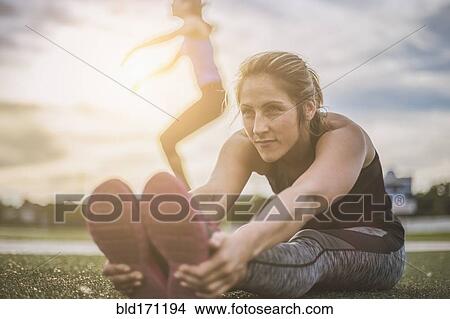 Picture - Athletes stretching on sports field. Fotosearch