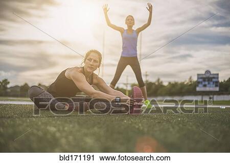 Stock Image - Athletes stretching on sports field. Fotosearch