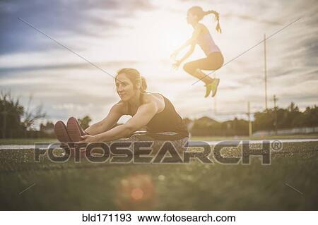 Stock Image - Athletes stretching on sports field. Fotosearch
