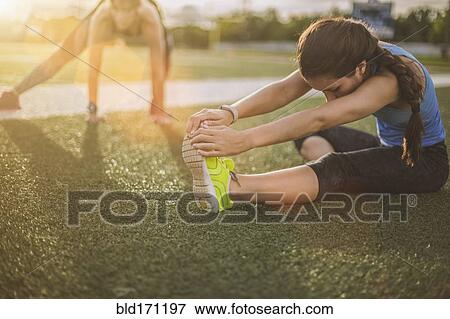 Stock Photo - Athletes stretching on sports field. Fotosearch