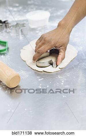 Baker using cookie cutter in dough View Large Photo Image Stock Photo - Baker using cookie cutter in dough. Fotosearch