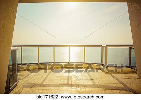 Stock Image - Balcony overlooking ocean and sunny sky. Fotosearch