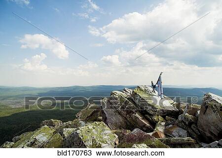 Stock Image - Banner on rocky hilltop in remote landscape. Fotosearch