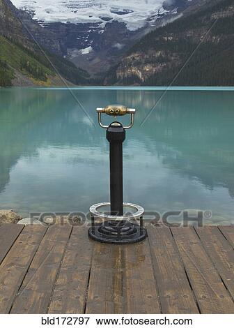 Stock Photo - Binoculars overlooking still lake in rural landscape . Fotosearch