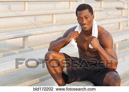Stock Image - Black athlete sitting on bleachers. Fotosearch