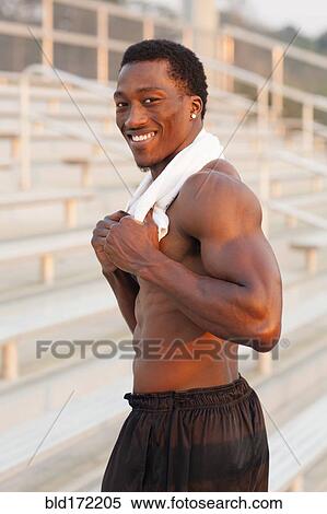 Stock Photography - Black athlete smiling on bleachers. Fotosearch