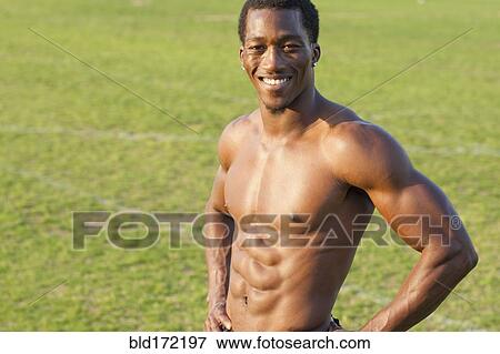 Stock Photo - Black athlete smiling on sports field. Fotosearch