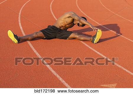 Stock Photo - Black athlete stretching on track in sports field. Fotosearch