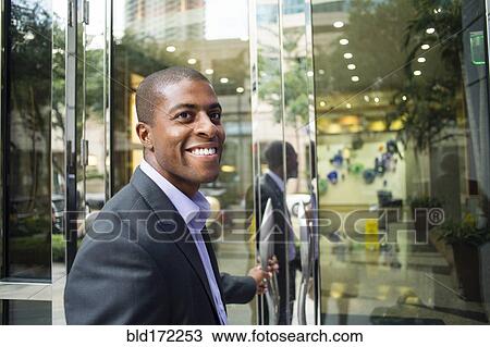 Stock Image - Black businessman opening office doors. Fotosearch