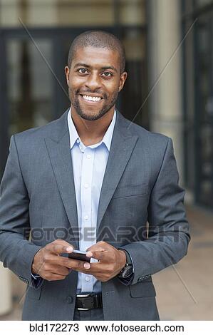 Black businessman using cell phone in city View Large Photo Image Stock Image - Black businessman using cell phone in city. Fotosearch
