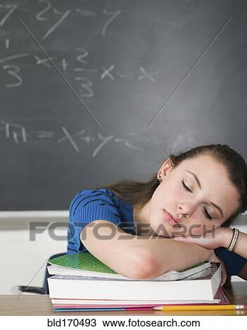 Stock Image - Bored student sleeping at desk in classroom. Fotosearch