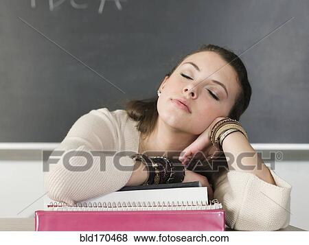 Stock Photo - Bored student sleeping at desk in classroom. Fotosearch