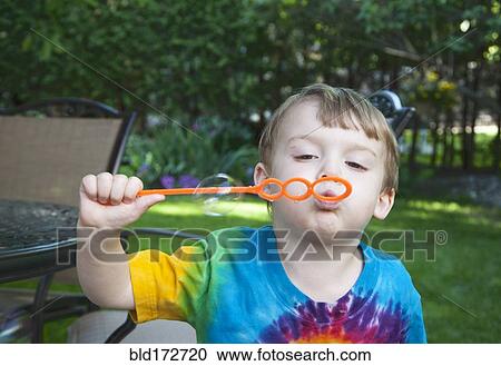 Boy blowing bubbles in backyard View Large Photo Image Stock Image - Boy blowing bubbles in backyard. Fotosearch