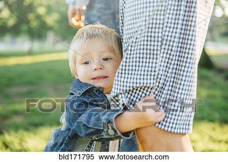 Boy clutching leg of father in grass in park View Large Photo Image Stock Photography - Boy clutching leg of father in grass in park. Fotosearch