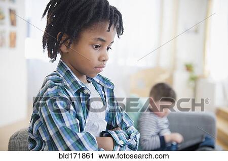 Boy ignoring friend in living room View Large Photo Image Stock Image - Boy ignoring friend in living room. Fotosearch