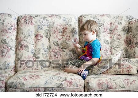 Picture - Boy playing with cell phone on sofa. Fotosearch