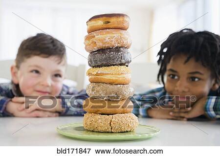 Boys admiring stack of donuts on counter View Large Photo Image Stock Photo - Boys admiring stack of donuts on counter. Fotosearch