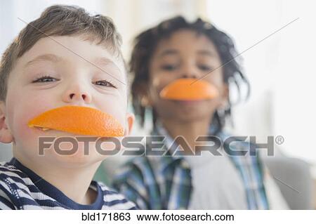 Stock Image - Boys biting orange slices. Fotosearch