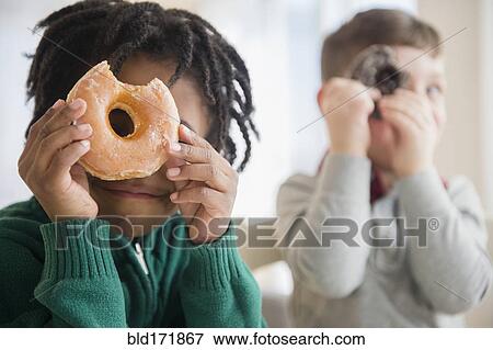 Stock Photo - Boys peering through donut holes. Fotosearch