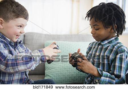 Stock Photo - Boys playing video games on sofa. Fotosearch