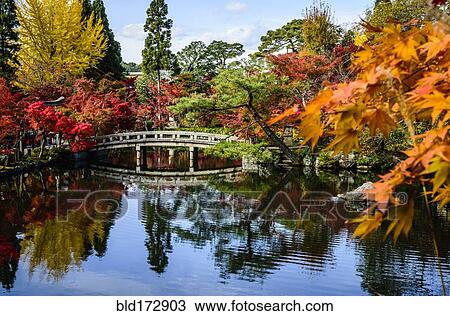 Stock Image - Bridge reflecting in still pond in park. Fotosearch