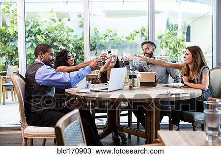 Stock Image - Business people toasting at lunch in cafe. Fotosearch