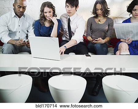Picture - Business people using laptop in office lounge. Fotosearch