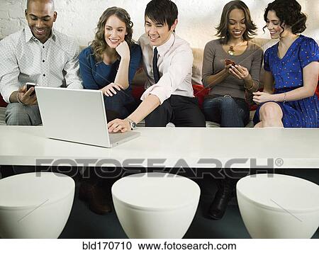 Stock Image - Business people using laptop in office lounge. Fotosearch